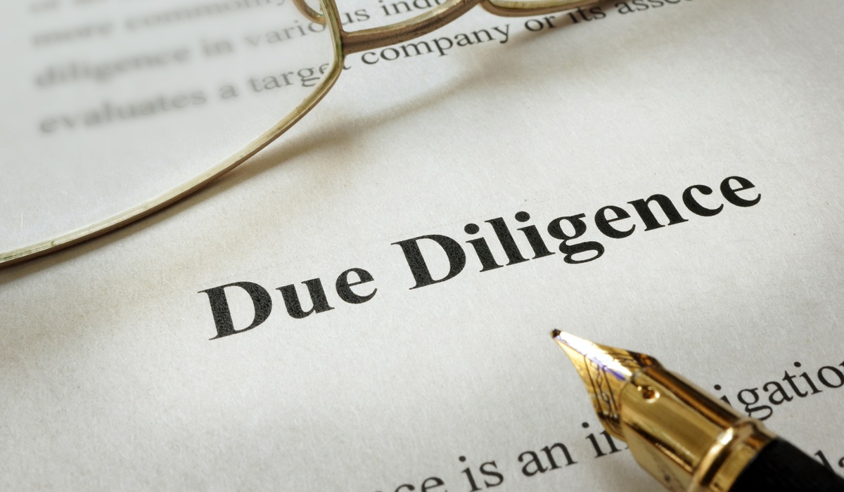 Page of paper with words Due Diligence and glasses.
